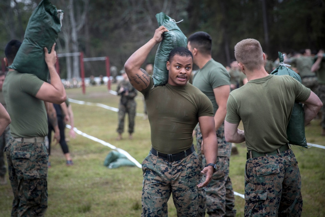 Marines and sailors carry weighted sandbags.