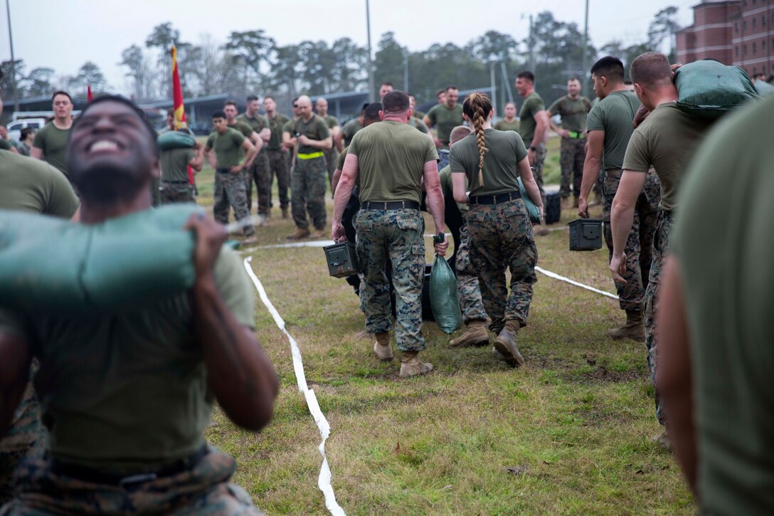 Marines and sailors carry ammo cans and weighted sandbags.