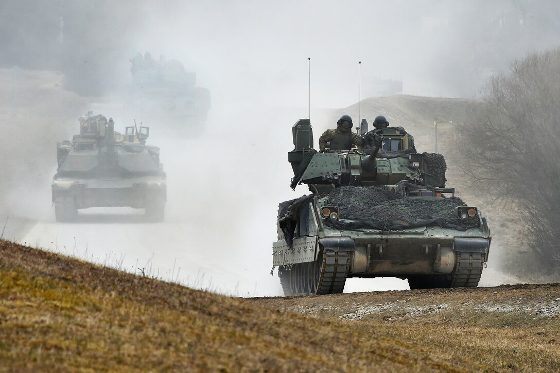 Soldiers maneuver an M2 Bradley fighting vehicle and an M1A1 Abrams tank.