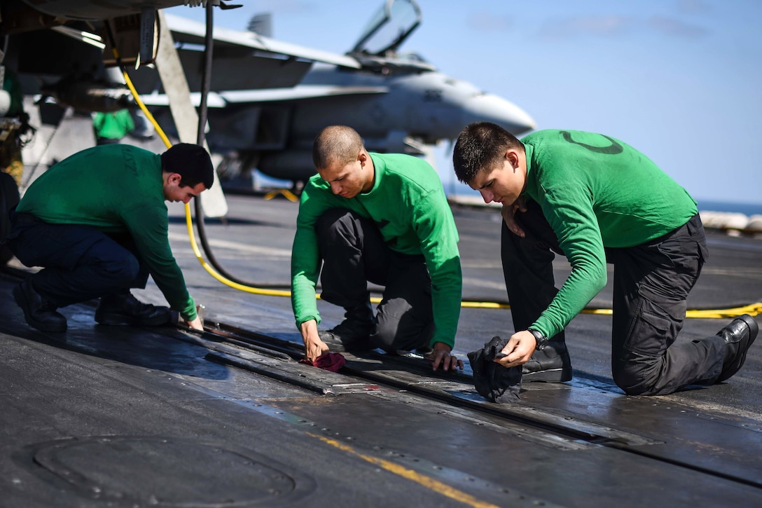 Sailors clean a catapult on the flight deck.