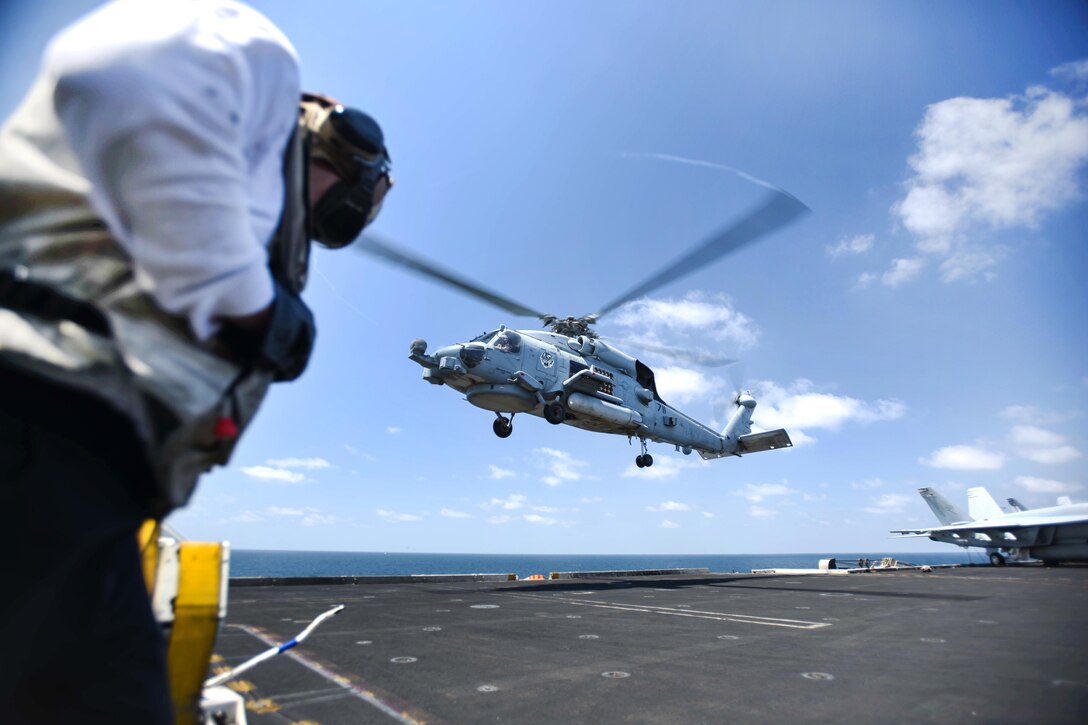 An MH-60R Sea Hawk helicopter rises from the flight deck.