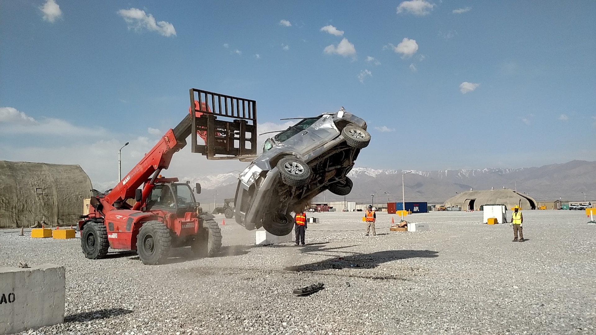Personnel use a large forklift to lift a vehicle and let it roll after being dropped to shake loose any ammunition that may have been left behind in the vehicles before any unfired rounds can cause an accident during disposal.