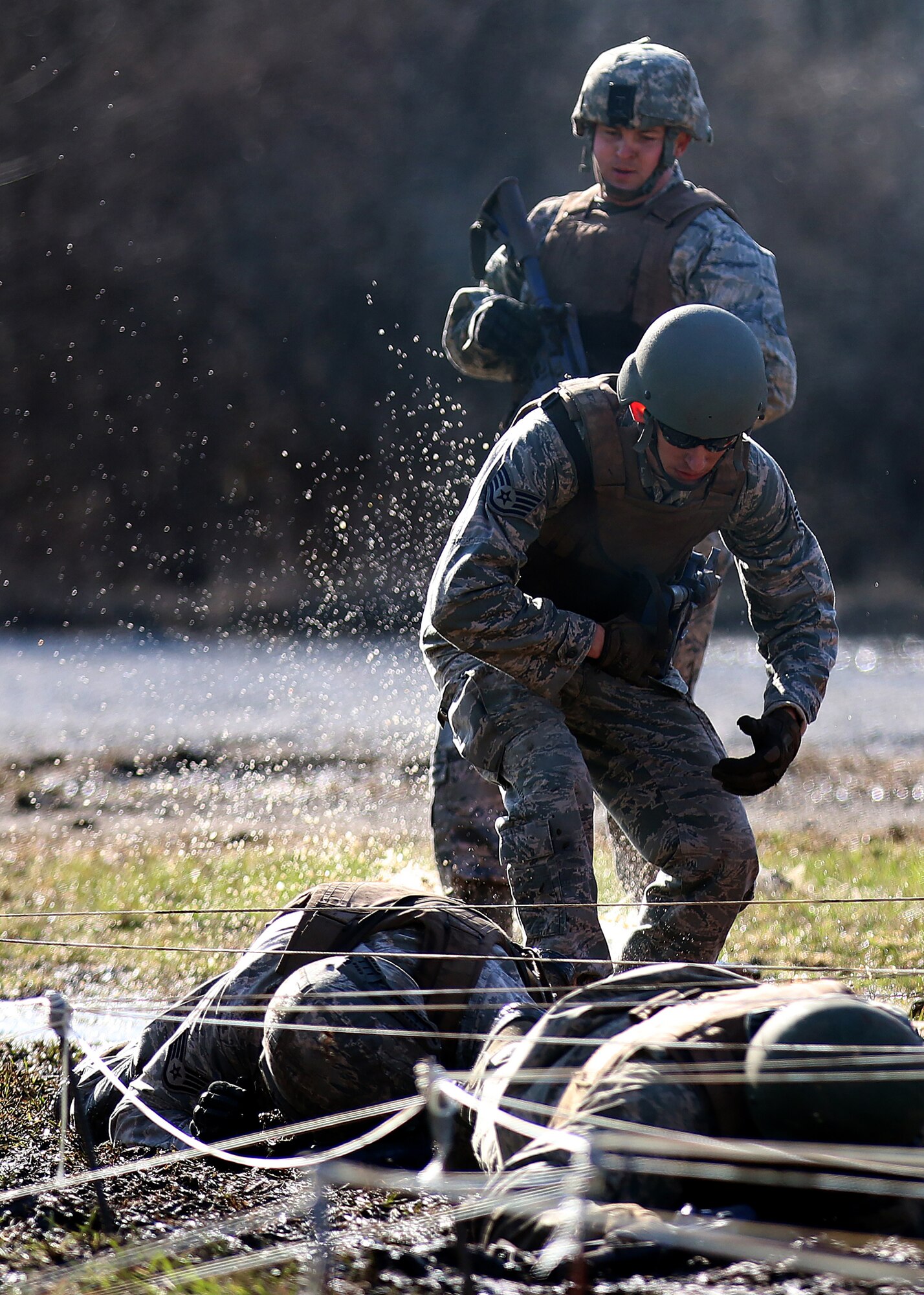 Staff Sgts. Tyler Heath (top) and Jonathan Prather, 445th Security Forces Squadron, prepare to hit the ground with purpose as they go into a low crawl under wire during the winter challenge exercise March 2, 2018