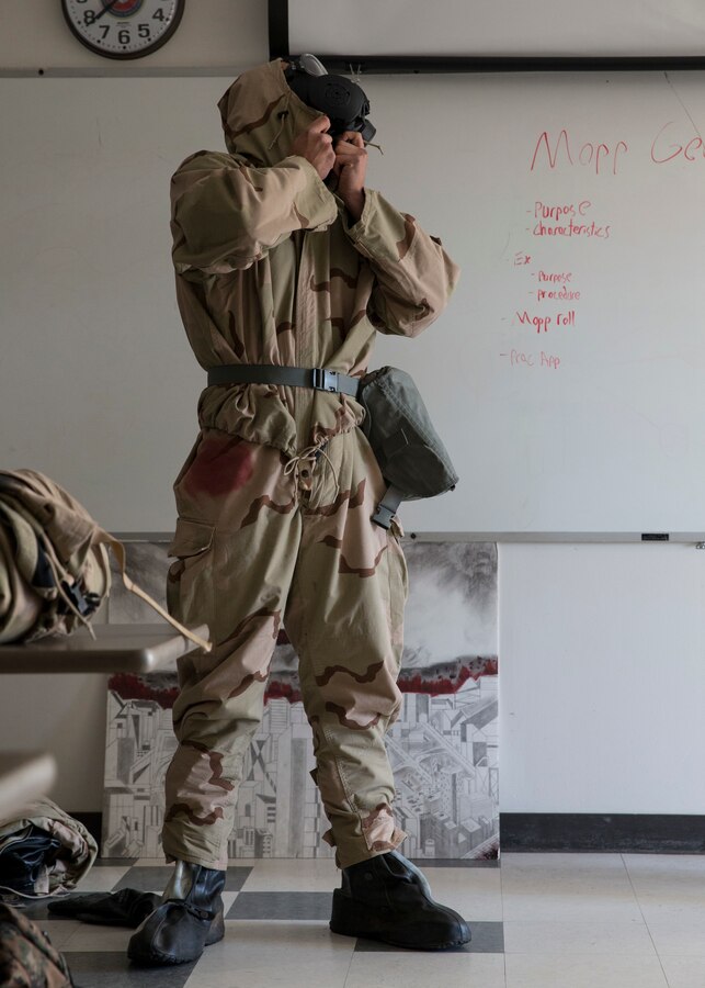 Lance Cpl. Anthony Soucy, a cyber network operator with 3rd Marine Aircraft Wing, demonstrates how to properly don a Mission Oriented Protective Posture suit during the reconnaissance, surveillance and decontamination course at Marine Corps Air Station Miramar, Calif., March 25. The course is designed to train unit personnel in the procedures and equipment used in accomplishing RS&D operations in a chemical, biological, radiological or nuclear environment. (U.S. Marine Corps photo by Lance Cpl. Clare J. McIntire)