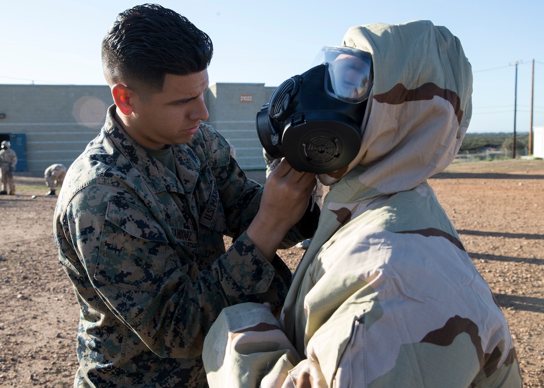 Pfc. Luis Sandoval, a cyber network operator with 3rd Marine Aircraft Wing, helps a Marine don a Mission Oriented Protective Posture suit during the reconnaissance, surveillance and decontamination course at Marine Corps Air Station Miramar, Calif., March 25. The course is designed to train unit personnel in the procedures and equipment used in accomplishing RS&D operations in a chemical, biological, radiological or nuclear environment. (U.S. Marine Corps photo by Lance Cpl. Clare J. McIntire)