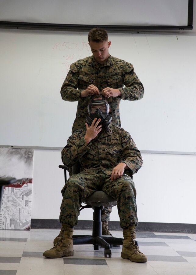 Cpl. Ashten Derickson, a cyber network specialist, assists Lance Cpl. Anthony Soucy, a chemical biological radiation defense specialist, both with 3rd Marine Aircraft Wing, in demonstrating proper fit of a M50 Joint Service General Purpose Mask during the reconnaissance, surveillance and decontamination course at Marine Corps Air Station Miramar, Calif., March 25. The course is designed to train unit personnel in the procedures and equipment used in accomplishing RS&D operations in a chemical, biological, radiological or nuclear environment. (U.S. Marine Corps photo by Lance Cpl. Clare J. McIntire/Released)