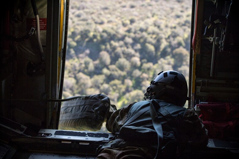 Tech. Sgt. Kevin Calloway, 71st Rescue Squadron HC-130J Combat King II loadmaster, throws a para-bundle out of the door of an HC-130J during Tiger Rescue IV, March 27, 2018, at Vandenberg Air Force Base, Calif. Para-bundles are typically used to deliver medical supplies to pararescumen on the ground. The four-day exercise challenged Airmen from multiple rescue squadrons to bring the capabilities of the personnel recovery triad together to successfully complete rescue missions and maintain proficiency. The three branches of the personnel recovery triad are the HC-130J, HH-60G Pave Hawk and the guardian angel weapons system or pararescuemen. (U.S. Air Force photo by Senior Airman Janiqua P. Robinson)