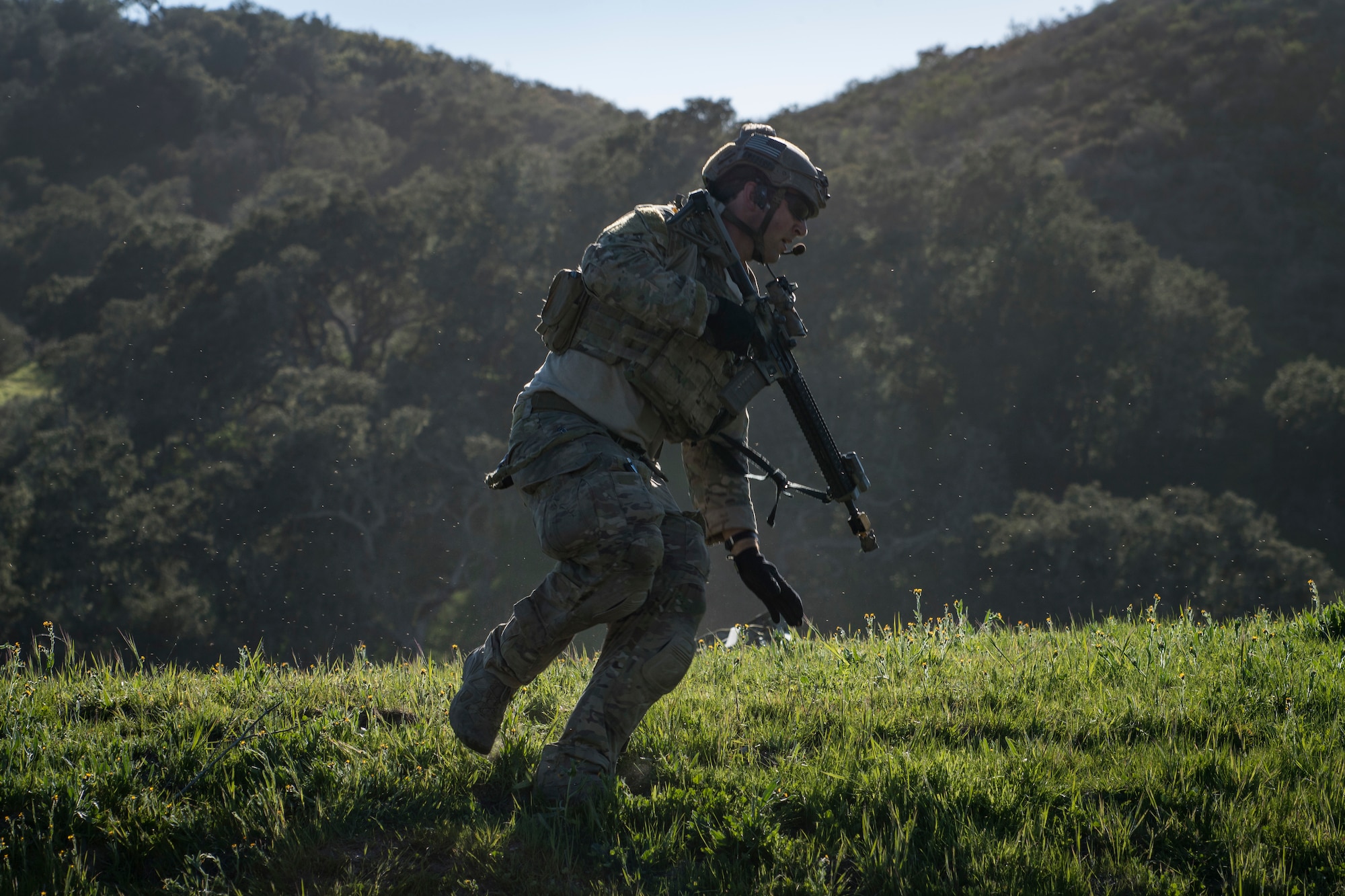 A pararescueman from the 58th Rescue Squadron, Nellis Air Force Base, Nev., runs for cover during Tiger Rescue IV, March 28, 2018, at Vandenberg Air Force Base, Calif. The four-day exercise challenged Airmen from multiple rescue squadrons to bring the capabilities of the personnel recovery triad together to successfully complete rescue missions and maintain proficiency. The three branches of the personnel recovery triad are the HC-130J Combat King II, HH-60G Pave Hawk and the guardian angel weapons system or pararescuemen. (U.S. Air Force photo by Senior Airman Janiqua P. Robinson)