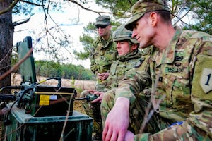 A British and two U.S. soldiers operate a remote device.