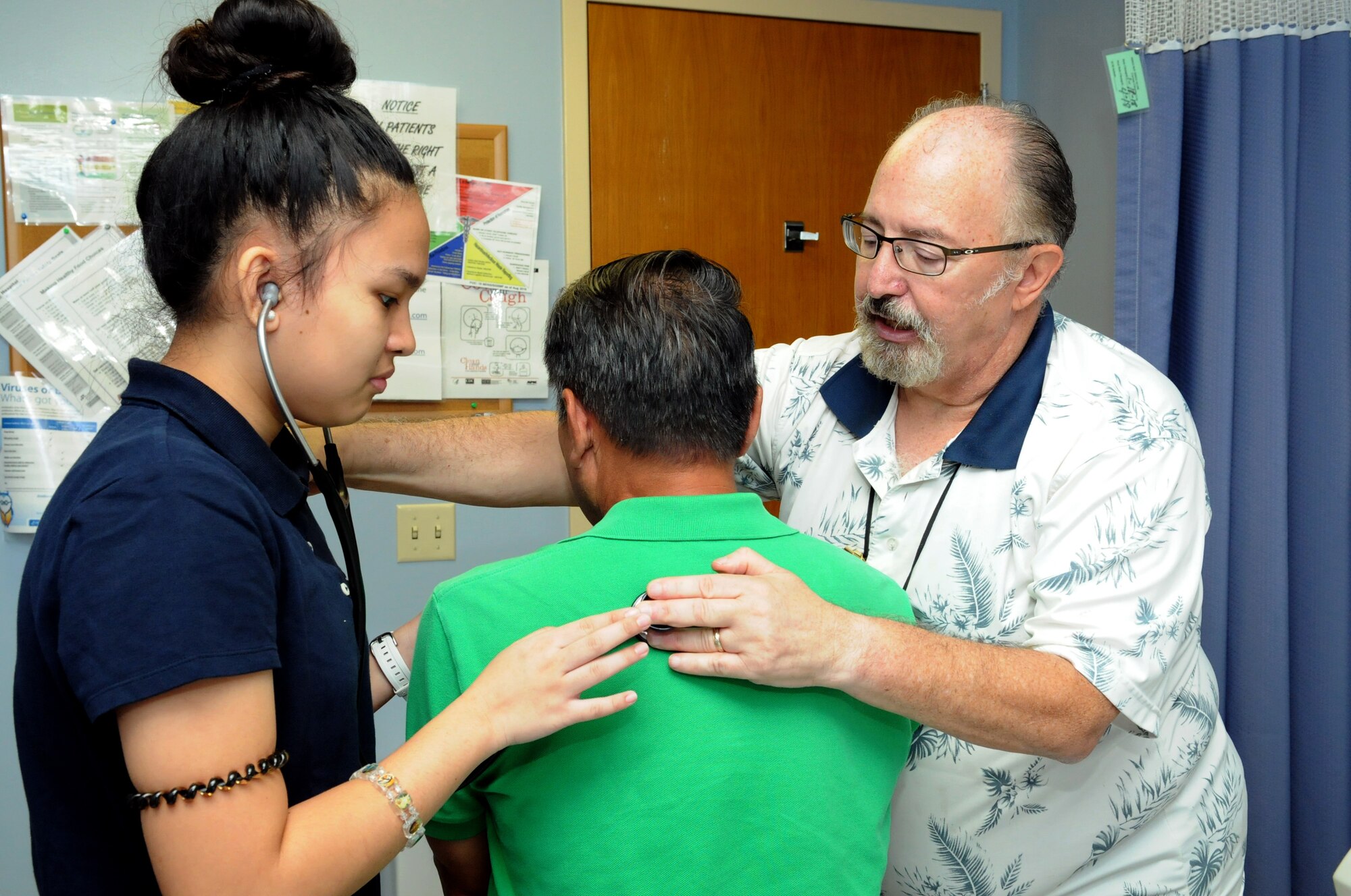 Queenie Ofiaza, a student from Radford High School, assists Dr. John L. Bossian, a staff physician with the 15th Medical Operations Squadron, in checking a patient during Career Shadow Day at the 15th Medical Group, Joint Base Pearl Harbor-Hickam, Hawaii, March 28, 2018.