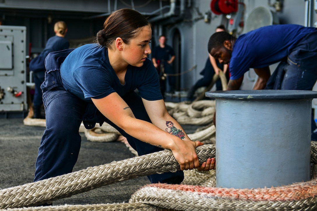 A sailor pulls at a mooring line.