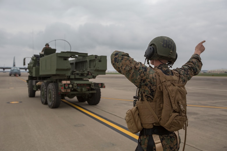 Marine Corps Sgt. Jeffery Hale, a launcher chief with Kilo Battery, 2nd Battalion, 14th Marine Regiment, directs a M142 High Mobility Artillery Rocket System (HIMARS) into position before being loaded onto an Air Force MC-130, on Fort Campbell, Ky., March 30, 2018. Marines from Kilo Battery flew from Fort Campbell to Dugway Proving Grounds, Utah, where they offloaded and fired four HIMARS missiles, demonstrating a unique capability that will give commanders more options to deal with threats when other options are not appropriate. (Marine Corps photo by Lance Cpl. Niles Lee)