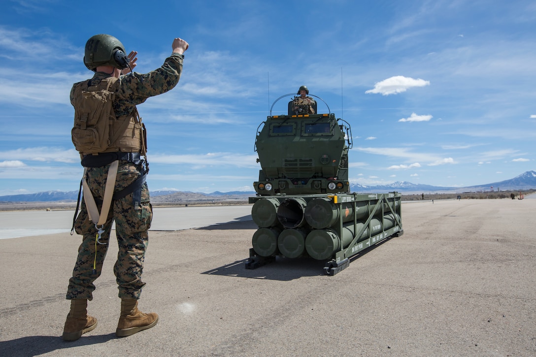 Marine Corps Sgt. Jeffery Hale, a launcher chief with Kilo Battery, 2nd Battalion, 14th Marine Regiment, directs a Marine Corps an M142 High Mobility Artillery Rocket System (HIMARS) into position to pick up missile pods, at Dugway Proving Grounds, Utah, March 30, 2018. Marines from Kilo Battery flew from Fort Campbell, Ky., to Dugway where they offloaded and fired four HIMARS missiles, demonstrating a unique capability that will give commanders more options to deal with threats when other options are not appropriate. (Marine Corps photo by Lance Cpl. Niles Lee)