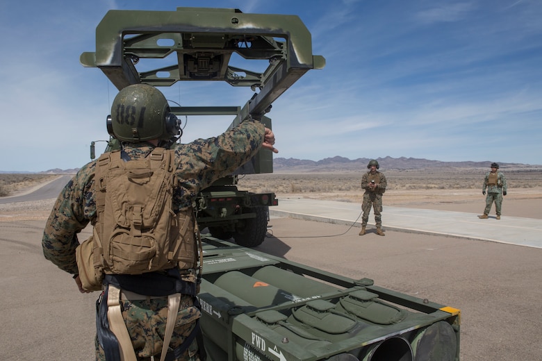 Marine Corps Sgt. Jeffery Hale, a launcher chief with Kilo Battery, 2nd Battalion, 14th Marine Regiment, signals for Cpl. Kyle Thompson, a gunner with Kilo Battery, to lower the hoist on an M142 High Mobility Artillery Rocket System (HIMARS) to pick up missile pods, at Dugway Proving Grounds, Utah, March 30, 2018. Marines from Kilo Battery flew from Fort Campbell, Ky., to Dugway where they offloaded and fired four HIMARS missiles, demonstrating a unique capability that will give commanders more options to deal with threats when other options are not appropriate. (Marine Corps photo by Lance Cpl. Niles Lee)
