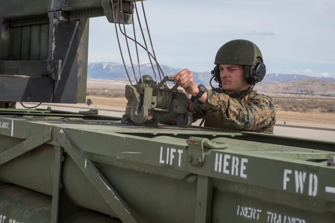 Marine Corps Sgt. Jeffery Hale, a launcher chief with Kilo Battery, 2nd Battalion, 14th Marine Regiment, hooks missile pods to a hoist on an M142 High Mobility Artillery Rocket System (HIMARS) at Dugway Proving Grounds, Utah, March 30, 2018. Marines from Kilo Battery flew from Fort Campbell, Ky., to Dugway where they offloaded and fired four HIMARS missiles, demonstrating a unique capability that will give commanders more options to deal with threats when other options are not appropriate. (Marine Corps photo by Lance Cpl. Niles Lee)