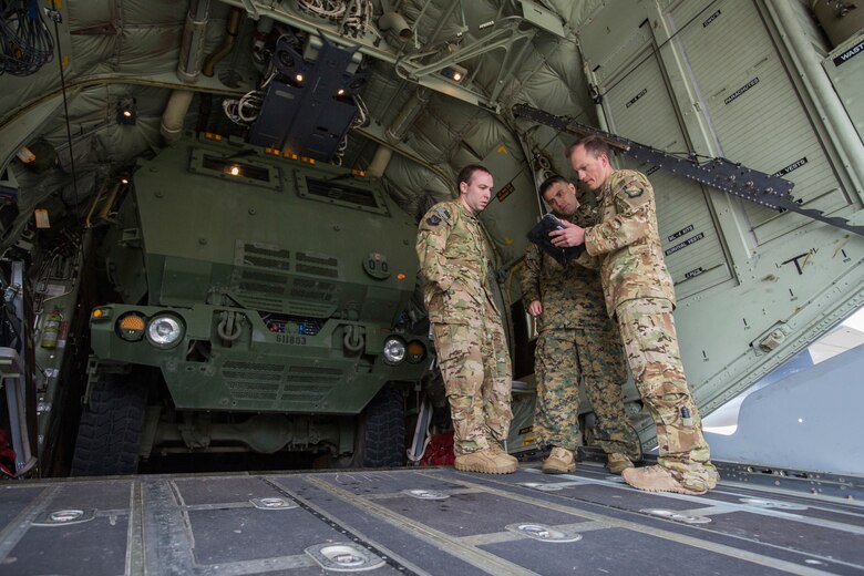 Air Force Pilots, Capt. Justin Burrier (left) and Capt. Jacob Wiseman (right), 9th Special Operations Squadron, discuss flight plans with Marine Corps Gunnery Sgt. Paul Hendee (center), an artillery operations chief with Kilo Battery, 2nd Battalion, 14th Marine Regiment, at Fort Campbell, Ky., March 29, 2018. Marines from Kilo Battery used an Air Force MC-130 to conduct a live-fire raid at Dugway Proving Ground, Utah, flying from Fort Campbell, to Dugway. There, they offloaded and fired four HIMARS missiles, demonstrating a unique capability that will give commanders more options to deal with threats when other options are not appropriate. (Marine Corps photo by Lance Cpl. Niles Lee)