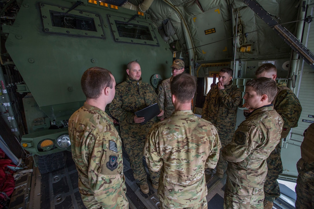Airmen from 9th Special Operations Squadron and Marines from Kilo Battery, 2nd Battalion, 14th Marine Regiment, discuss flight plans at Fort Campbell, Ky., March 29, 2018. Marines from Kilo Battery used an Air Force MC-130 to conduct a live-fire raid at Dugway Proving Ground, Utah, flying from Fort Campbell, to Dugway. There, they offloaded and fired four HIMARS missiles, demonstrating a unique capability that will give commanders more options to deal with threats when other options are not appropriate. (Marine Corps photo by Lance Cpl. Niles Lee)