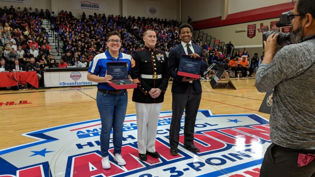 Staff Sgt. Brandon Hall-Wallace, a recruiter at Recruiting Substation Northeast, stands with Angela Tapia and Chase Griffin during the High School Slam Dunk and 3-Point Championship at Karen Wagner High School in San Antonio, Texas, March 27, 2018. Tapia and Griffin were selected to attend the Battles Won Academy in the District of Washington in July, 2018.