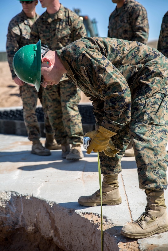 A Marine measures the depth of a concrete crater.