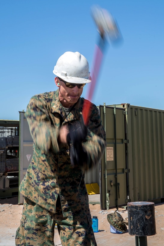 A Marine hammers a spike into the ground.