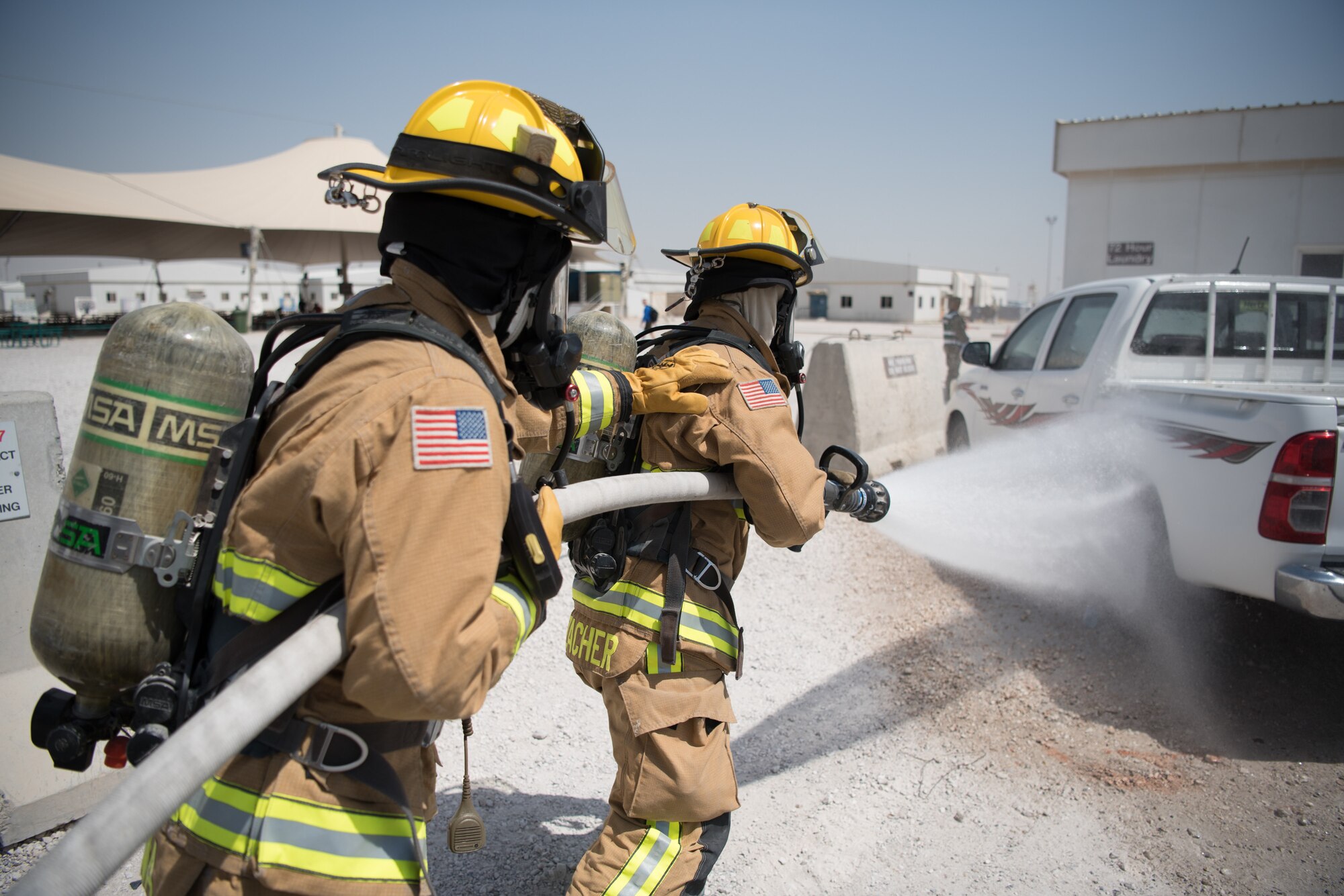 Firefighters from the 379th Expeditionary Civil Engineer Squadron extinguish a simulated fire during an attack notification response exercise at Al Udeid Air Base, Qatar, March 22, 2018. The scenario, commenced in a realistic and unanticipated manner, was designed to improve physical and procedural security as well as warning and alert notification capabilities. (U.S. Air Force photo by Staff Sgt. Joshua Horton)