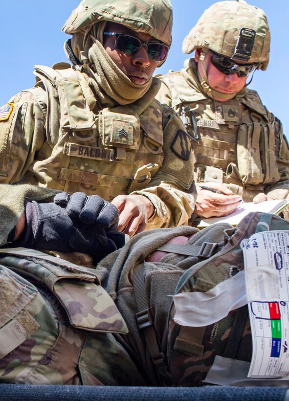 A soldier monitors a mock patient during a casualty evacuation exercise.