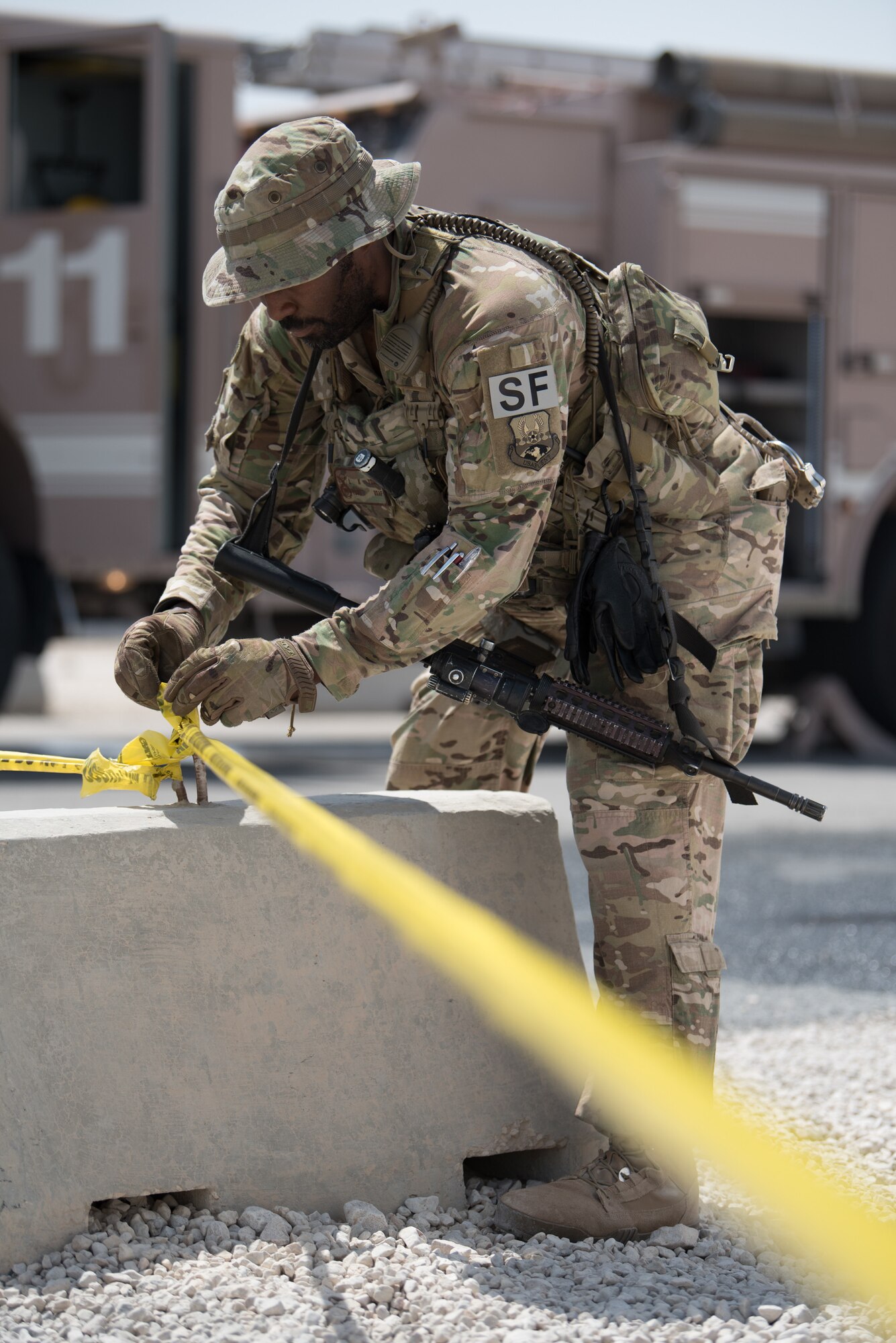 A 379th Air Expeditionary Security Forces Squadron Airman sets up a cordon during an attack notification response exercise at Al Udeid Air Base, Qatar, March 22, 2018. The scenario, commenced in a realistic and unanticipated manner, was designed to improve physical and procedural security as well as warning and alert notification capabilities. (U.S. Air Force photo by Staff Sgt. Joshua Horton)
