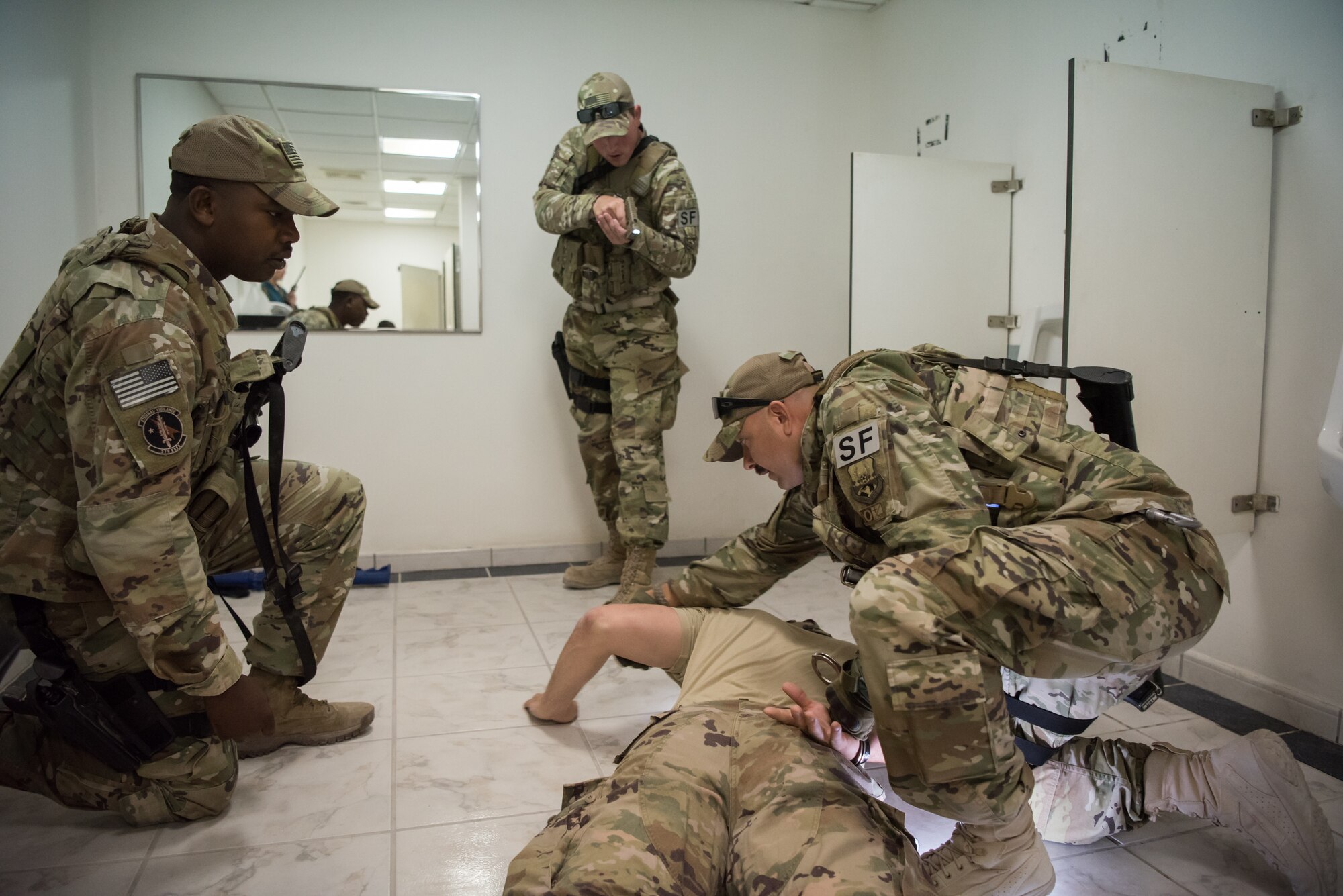 Airmen from the 379th Air Expeditionary Security Forces Squadron apprehend a simulated active shooter during an attack notification response exercise at Al Udeid Air Base, Qatar, March 22, 2018. The scenario, commenced in a realistic and unanticipated manner, was designed to improve physical and procedural security as well as warning and alert notification capabilities. (U.S. Air Force photo by Staff Sgt. Joshua Horton)