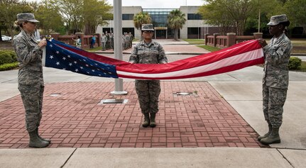 Airman Cierra Benak, left, 16th Airlift Squadron aviation resource manager technician, Airman 1st Class Beatrix Bainter, center, 628th Force Support Squadron management technician, and Airman 1st Class Julie-Ann Banton, right, 628th Air Base Wing paralegal specialist, fold the U.S. flag during a retreat ceremony March 30, 2018, at Joint Base Charleston, S.C.