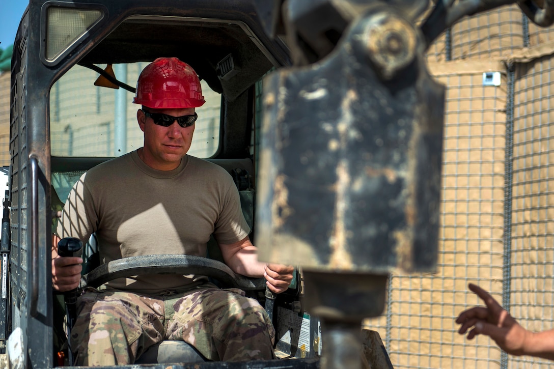 A soldier operates an auger dirt driller.