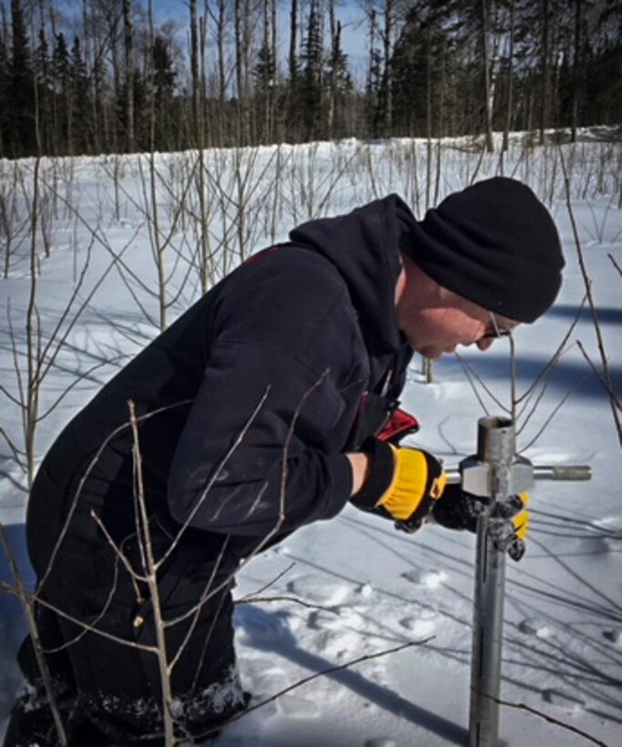 man surveys snow depth and content