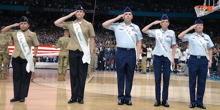 Members of the 2018 Joint Base San Antonio Ambassadors salute during the National Anthem as part of the pregame ceremonies at the NCAA Division I men's basketball championship game at the Alamodome Monday, April 2, 2018. From left are Petty Officer 2nd Class Diana Mendoza Se Saenz, Petty Officer 1st Class Shannon Chatterton, Tech. Sgt. Christofer Mercado, Tech. Sgt. Melissa Bennett and Petty Officer 1st Class Victoria Toth.