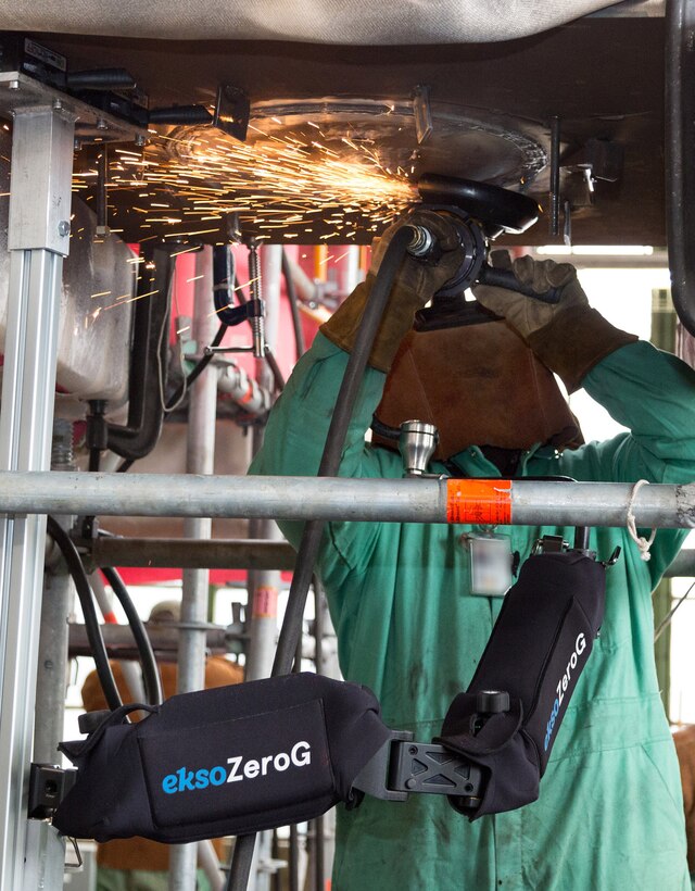 A Puget Sound Naval Shipyard & Intermediate Maintenance Facility worker demonstrates to managers, process improvement specialists and trades people how the Ekso zeroG Arm can be used to reduce injuries and increase productivity during a technology trial Feb. 26-28 at the shipyard in Bremerton, Washington. For the demonstration, the grinder was supported by the arm, which was attached to the simulated bulkhead with switchable magnetic bases. The arm can support up to 42-pound tools and absorbs up to 25 percent of the tool’s vibration. (U.S. Navy photo by Carie Hagins, PSNS & IMF photographer)