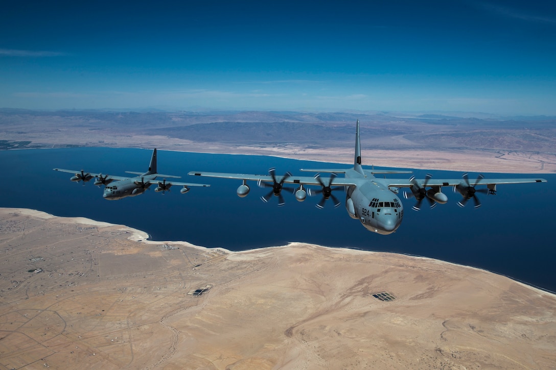 Two aircraft fly over coastline and water.