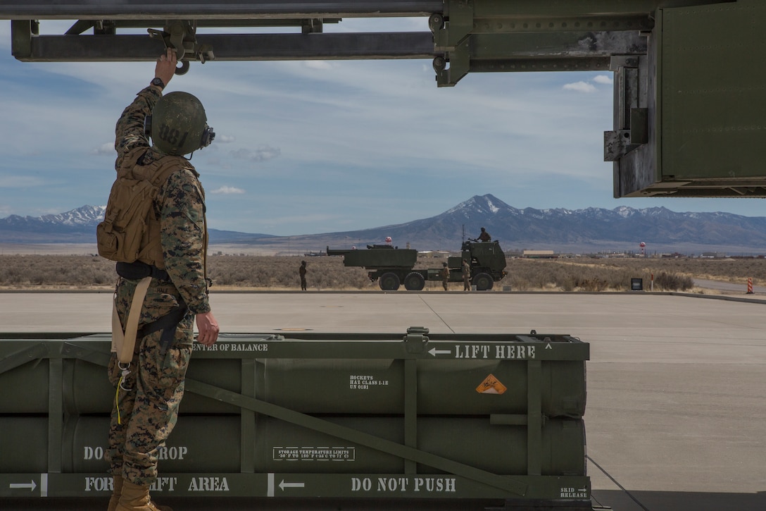 Marine Corps Sgt. Jeffery Hale, a launcher chief with Kilo Battery, 2nd Battalion, 14th Marine Regiment, guides a hoist up on an M142 High Mobility Artillery Rocket System (HIMARS) after dropping off a missile pod, at Dugway Proving Grounds, Utah, March 30, 2018. Marines from Kilo Battery flew from Fort Campbell, Ky., to Dugway where they offloaded and fired four HIMARS missiles, demonstrating a unique capability that will give commanders more options to deal with threats when other options are not appropriate.
