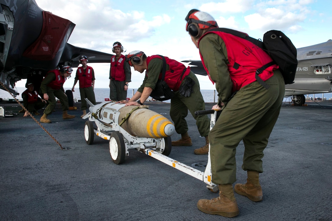 Marines prepare to mount a bomb onto an aircraft.