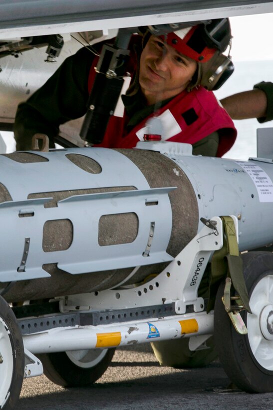 Marines mount a 1,000-pound guided bomb onto an aircraft.