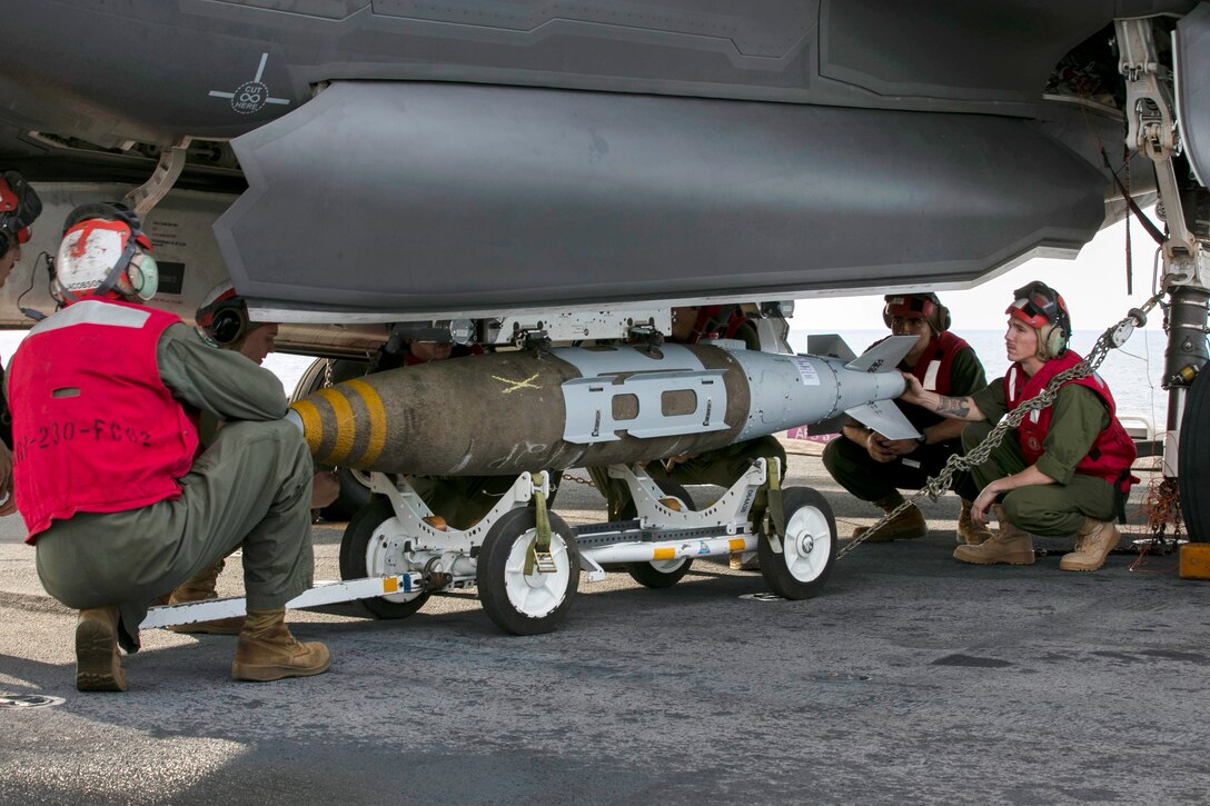 Marines mount a 1,000-pound guided bomb onto an aircraft.