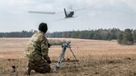 Kneeling soldier watches a drone in flight.
