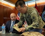 Army Col. Brian Kim, senior veterinary advisor, demonstrates the heater in a “meal, ready to eat” field ration for Mike Scott, deputy director of DLA Logistics Operations, at a lunch-and-learn event at DLA headquarters April 4. Scott hosted team members who learned about combat rations, tried current menus and taste-tested potential future products. Photo by Jacob Boyer
