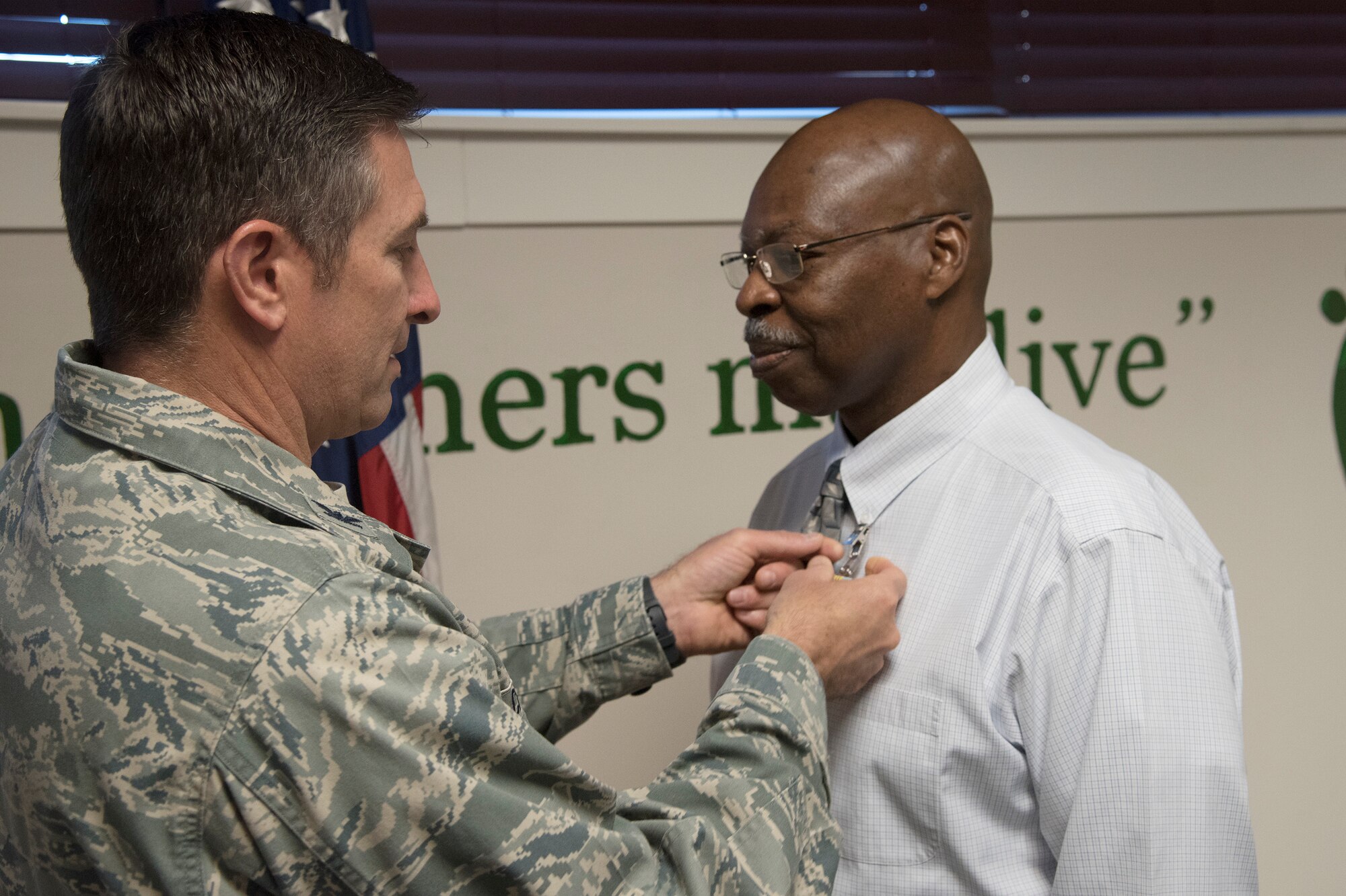 Col. John Chastain, left, 23d Maintenance Group (MXG) commander, places a medal on Arlonzo Nelson, 23d MXG computer assistant, during a retirement ceremony, March 29, 2018, at Moody Air Force Base, Ga. Nelson is retiring after 30 years of civilian service here. (U.S. Air Force photo by Airman Eugene Oliver)