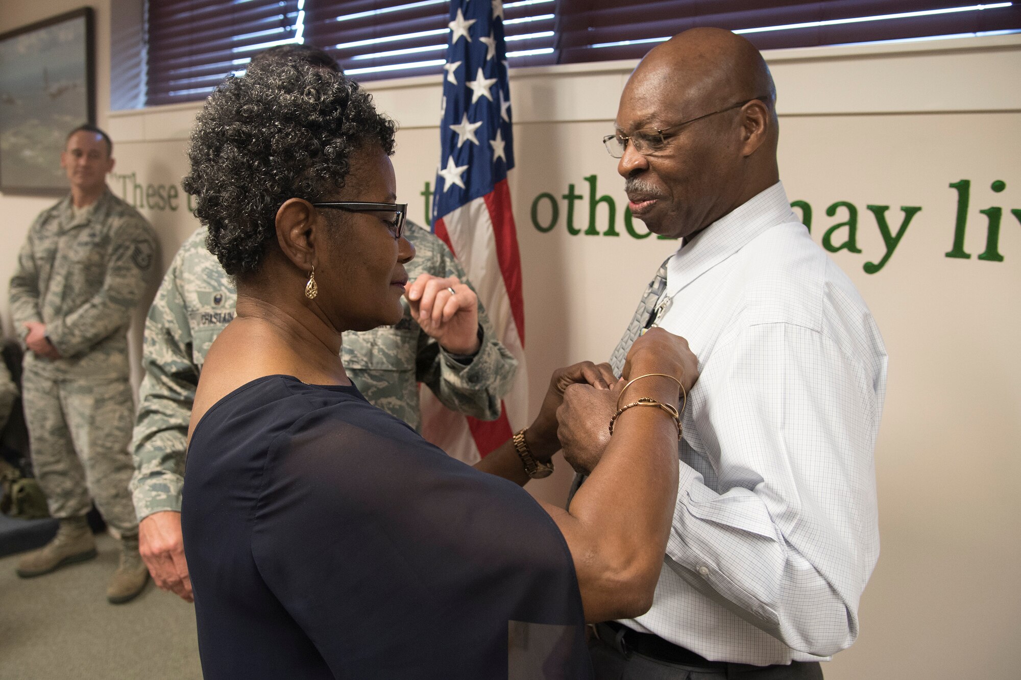 Cynthia Nelson, places a medal on her spouse, Arlonzo, 23d Maintenance Group computer assistant, during a retirement ceremony, March 29, 2018, at Moody Air Force Base, Ga. Nelson is retiring after 30 years of civilian service here. (U.S. Air Force photo by Airman Eugene Oliver)