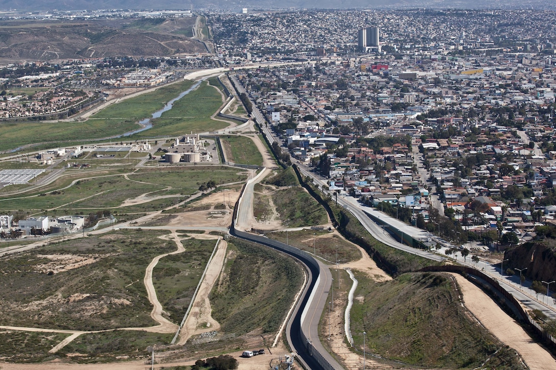 A wall separates a metropolitan area from a more sparsely developed one.