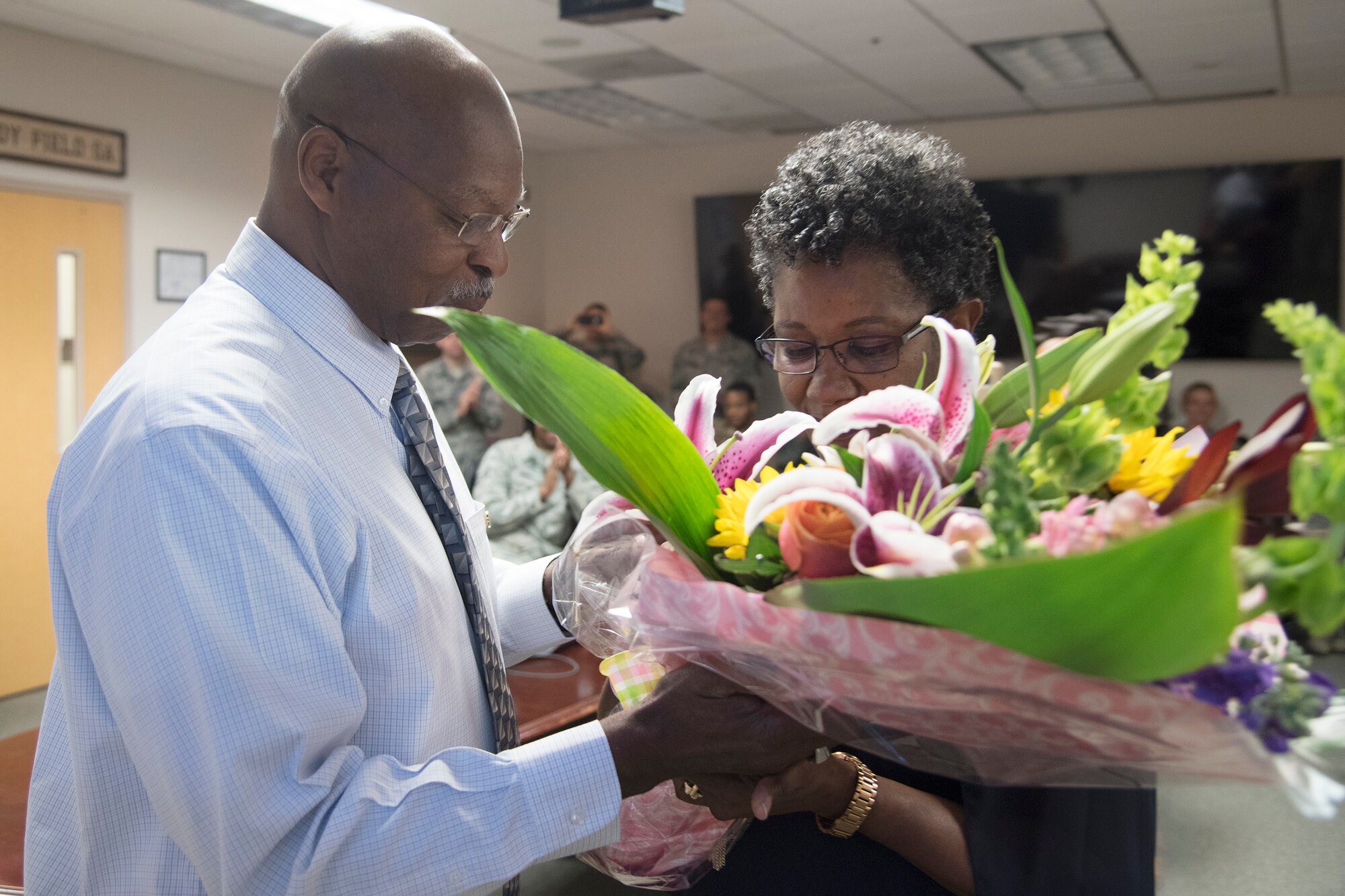 Arlonzo Nelson, left, 23d Maintenance Group computer assistant, hands flowers to his spouse Cynthia, during a retirement ceremony, March 29, 2018, at Moody Air Force Base, Ga. Nelson is retiring after 30 years of civilian service here. (U.S. Air Force photo by Airman Eugene Oliver)