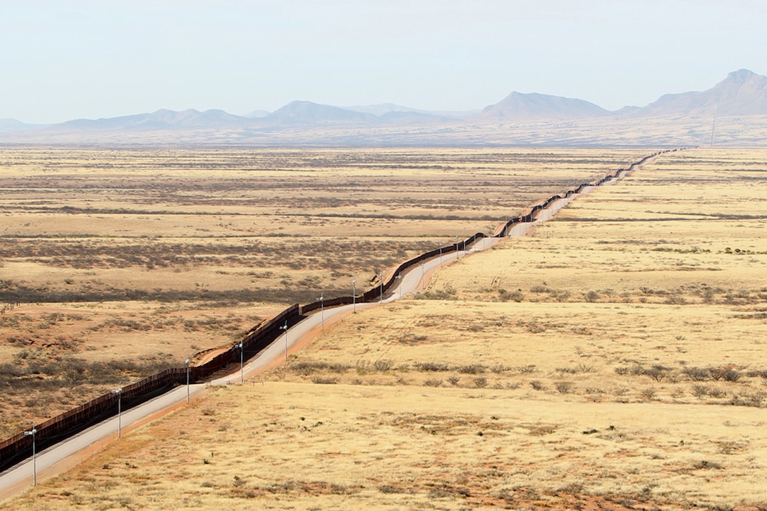 Dark brown fencing spans arid brown terrain.