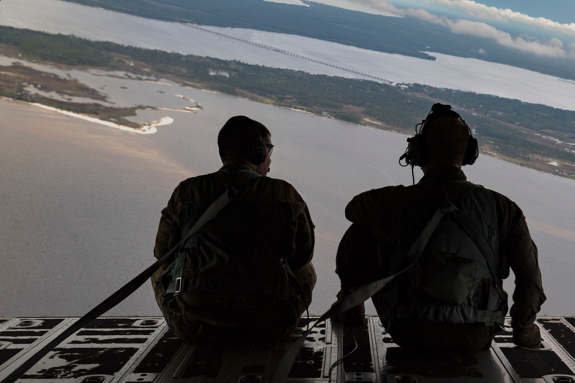 Staff Sgt. James Baker, left, and Master Sgt. Jeff Nieding, both 71st Rescue Squadron loadmasters, sit on the ramp in the rear of an HC-130J Combat King II, March 30, 2018, in the skies over Florida. As loadmasters, they are responsible for calculating aircraft weight and balance records, maintaining the cargo manifest, conducting cargo and personnel airdrops, and troubleshooting in-flight problems. (U.S. Air Force photo by Staff Sgt. Ryan Callaghan)