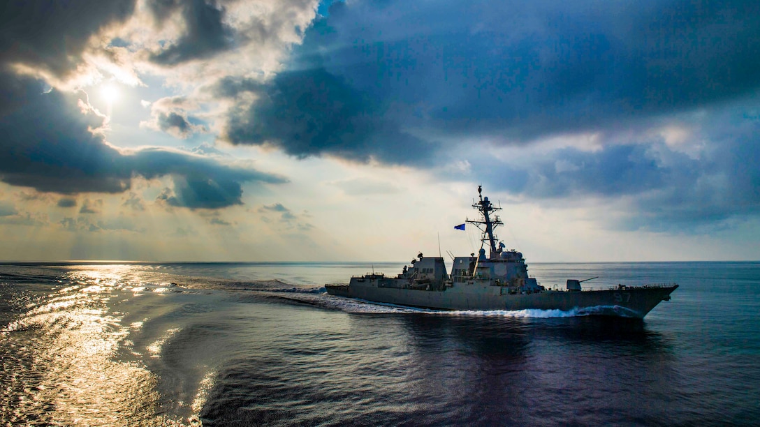 A destroyer travels in the ocean, making a curved pattern in its wake.