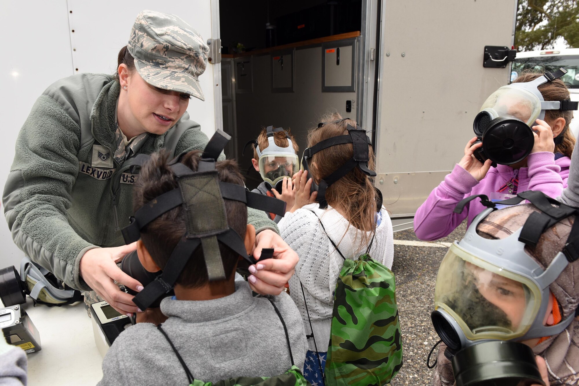 Staff Sgt. Ashley Lexvold, 30th Civil Engineer Squadron plans and operations, fits military children with protective masks during Kids Understanding Deployment Operations, April 4, 2018, Vandenberg Air Force Base, Calif. KUDOS is a program developed to give children a deeper understanding of the military deployment process and equipment utilized during a deployment. (U.S. Air Force photo by Tech. Sgt. Jim Araos/Released)