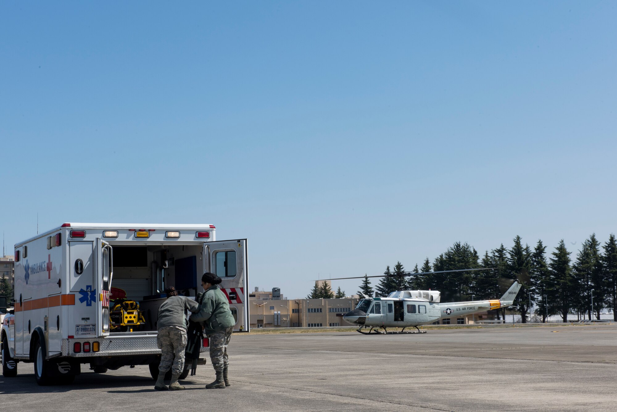 Members of the 374th Medical Group prepare to load a simulated patient into a UH-N1 Iroquois during helicopter transport training, March 30, 2018, at Yokota Air Base, Japan.