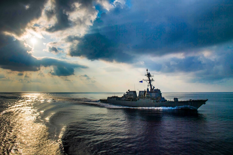 A destroyer travels in the ocean, making a curved pattern in its wake.